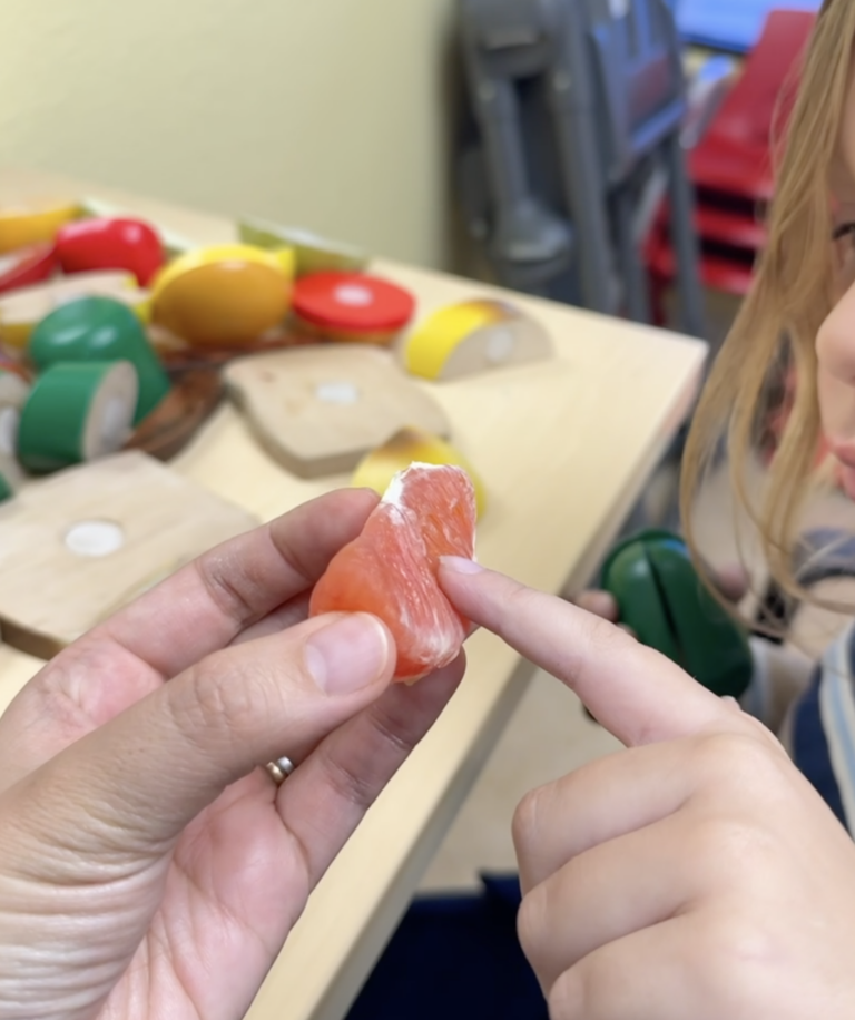 Therapist offers an orange wedge for a child to explore during SOS feeding therapy.